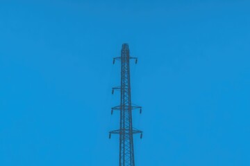 Obraz premium Metal electricity transmission tower against a clear blue sky