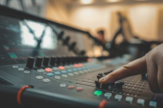 Close-up of a person adjusting sound levels on an audio mixing console during a live event or performance