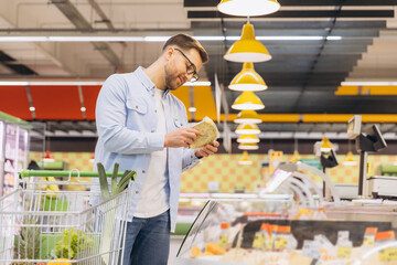 Customer choosing cheese in refrigerated section of supermarket