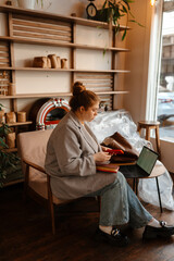 The female owner is holding the phone and sitting near the laptop on the table, preparing for the...