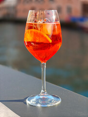 A glass of Aperol spritz cocktail on the table of a Venetian cafe. Venetian background