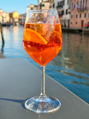 A glass of Aperol spritz cocktail on the table of a Venetian cafe. Venetian background