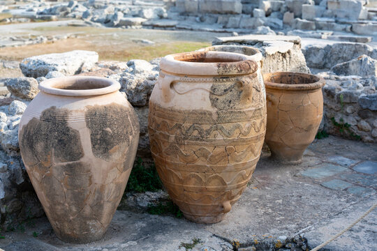 Four ancient Greek pottery jars (pithoi) with intricate patterns, resting in an archaeological ruin. The weathered textures highlight Greece's rich cultural and historical heritage.
