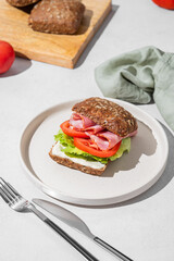 Toast club sandwich made of grain bread with prosciutto, cheese, tomatoes, lettuce and sauce on light background