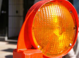 Orange-rote runde Absperrlampe für Verkehr in Stadt bei Sonne am morgen im Frühling