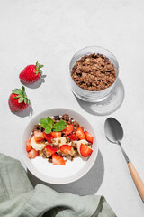 Natural Greek yogurt with homemade chocolate granola, strawberries and banana in a bowl
