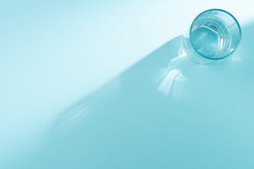 Glass of water on blue background. Flat lay, top view. Copy space