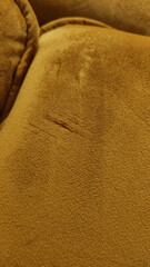 Detail of damaged mustard yellow velvet upholstery showing wear and tear of sofa