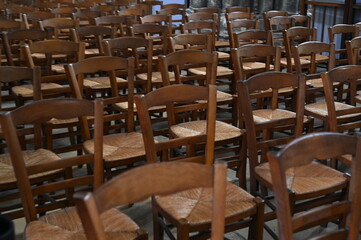 Rows of wooden chairs in an old church or hall. Vintage seating arrangement with warm wood tones and classic atmosphere, symbol of tradition, community, and history.