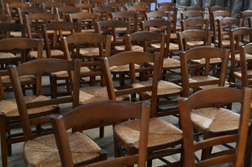 Rows of wooden chairs in an old church or hall. Vintage seating arrangement with warm wood tones and classic atmosphere, symbol of tradition, community, and history.