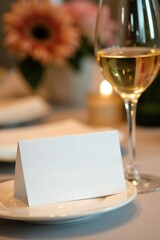 Blank card on plate beside wine glass and flowers