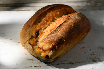 Golden crusted artisanal bread loaf resting on a rustic wooden surface illuminated by soft natural...