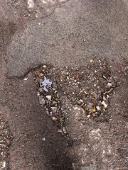 poor paved road with a lot of holes and potholes, poor transport infrastructure with an unrepaired road with a pit and a pothole