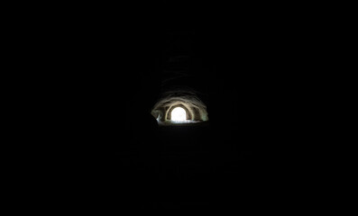 Light at the end of a dark tunnel reveals an intriguing sight in a mysterious underground setting