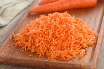Freshly grated carrot on wooden board (Selective Focus, Focus  in the middle of the image)
