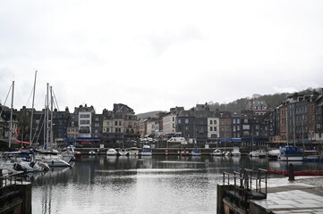 Scenic port town in France with colorful old houses and boats reflecting in the water. Traditional Normandy architecture and peaceful harbor atmosphere.