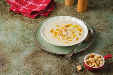 Cauliflower puree soup with white bread croutons and aromatic butter as a garnish in a light...