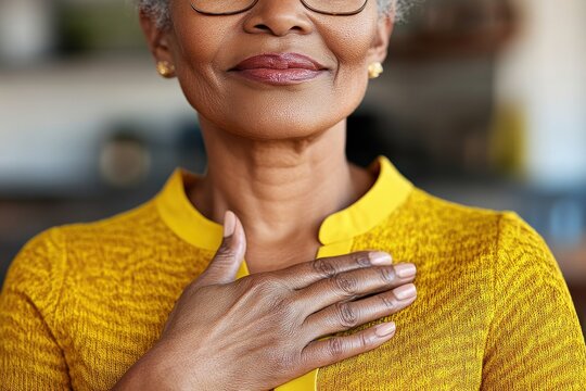 A Hispanic woman with a youthful and attractive appearance is captured in a close-up, cropped indoor shot, her folded palms on her chest expressing genuine feelings of gratitude
