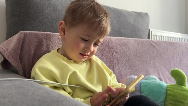 Little boy, cute child, watching video on phone and crying mischievously, negative impact of internet on toddler