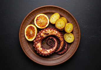 Professional top-down shot of grilled octopus and roasted potatoes, garnished with olive oil and lemon. Rustic plating stands out against the deep black backdrop in HD clarity.

