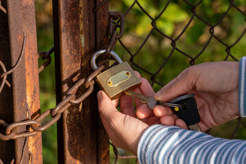 Woman hand holding key and unlocking padlock.