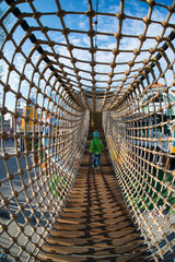 Child walking through rope bridge.