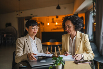 two multicultural businesswoman work together on new project indoor