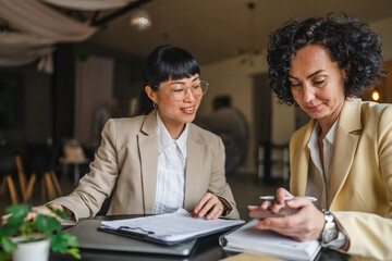 two multicultural businesswoman work together on new project indoor