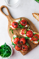 Bruschetta with cottage cheese, arugula and roasted cherry tomatoes. Food photo.