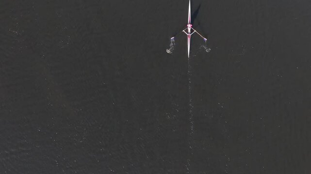 A single scull rowing in slow motion from the bottom to the top of the frame