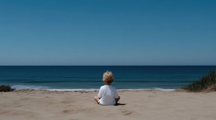 Child sits on beach, ocean view