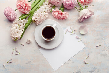 Flat lay with morning cup of coffee, empty card and bouquet of flowers on pastel concrete background. Top view, copy space