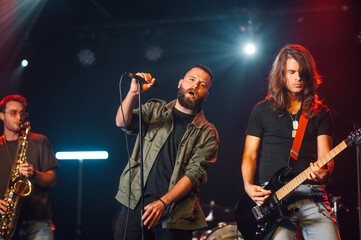 Rock band performing live on stage with saxophonist, singer and guitarist