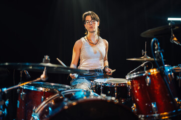 Female drummer performing energetically on stage with drum kit
