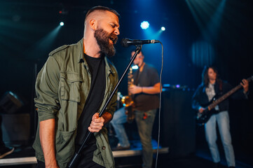 Fototapeta premium Singer performing with band on stage in nightclub
