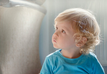 Sweet little child boy watching the dust particles in the morning light from the window
