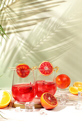 Royal cocktail of blood orange, ice cubes, rum and tequila. Summer party and restaurant relaxation concept. Menu for a bar or cafe. Banner with glasses of alcoholic drinks and tropical fruits.