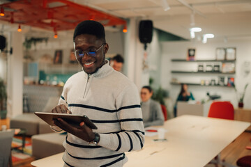 Smiling manager using digital tablet in modern office with coworkers