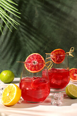 Flyer with glasses of alcoholic drinks and tropical fruits. Royal cocktail of blood orange, ice cubes, rum and tequila. Concept of summer party and rest in a restaurant. Menu for a bar or cafe