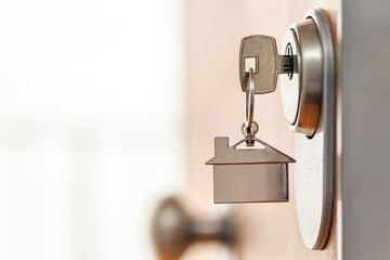 Close up of house key with keychain into door lock. Real estate and home security. Copy space.