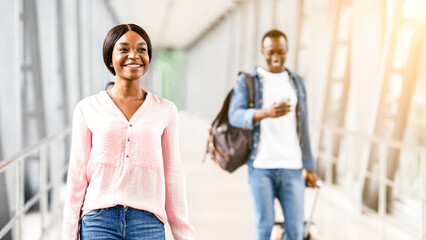 Travelling Concept. Happy Black Man And Woman Walking At Airport Terminal With Luggage, Ready For...
