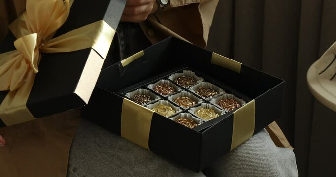 Woman opening gift box with candies at home, closeup