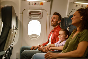 A cheerful family smiles on an airplane, embracing and enjoying their travel experience together as they journey