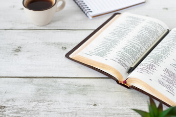 Open holy bible book with cup of coffee and notebook on wooden table. Christian Scripture study,...