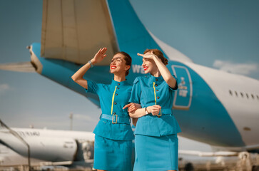 Two flight attendants in retro uniforms stand in front of a colorful airplane, showcasing airline history.