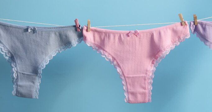 Beautiful panties hanging on clothes line against light blue background. Camera moving right
