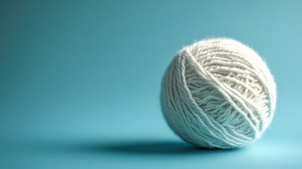 a soft white yarn ball on a smooth blue surface with its soft texture