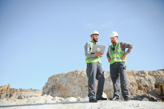 Portrait of stone quarry workers standing on the background of an excavator