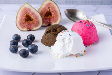 Colorful ice cream scoops on a plate with figs and blueberries.