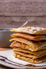 Close-up of a stack of waffles and a cup of coffee behind.
